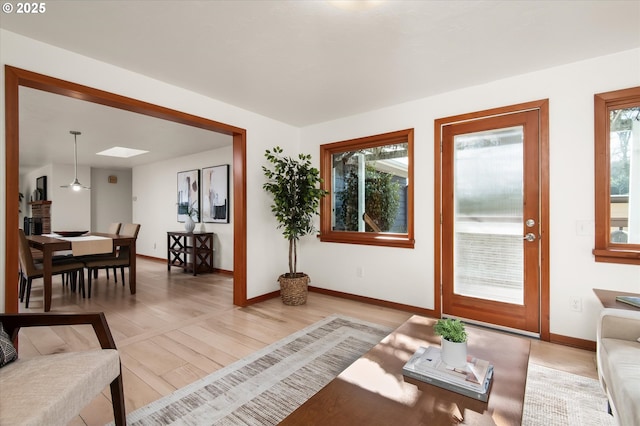 living room featuring light wood-type flooring and a skylight