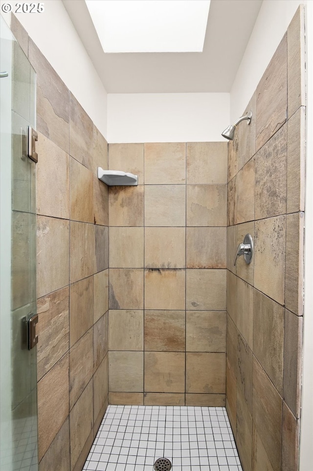 bathroom with a tile shower and a skylight