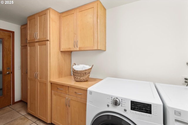 washroom with light tile patterned floors, washer and clothes dryer, and cabinets