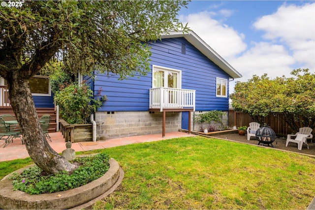 back of house with a yard, a patio area, and a fire pit