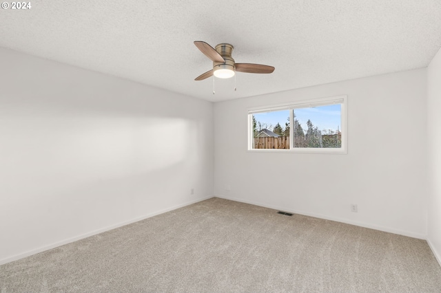 carpeted empty room featuring ceiling fan and a textured ceiling