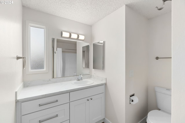 bathroom with vanity, toilet, and a textured ceiling