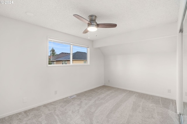 interior space with a textured ceiling, light colored carpet, ceiling fan, and lofted ceiling