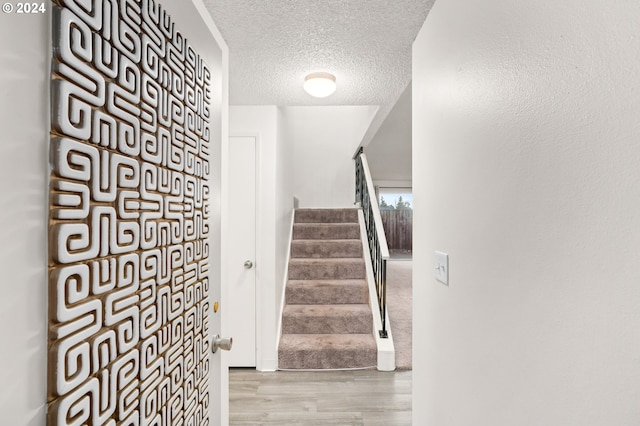 staircase featuring wood-type flooring and a textured ceiling