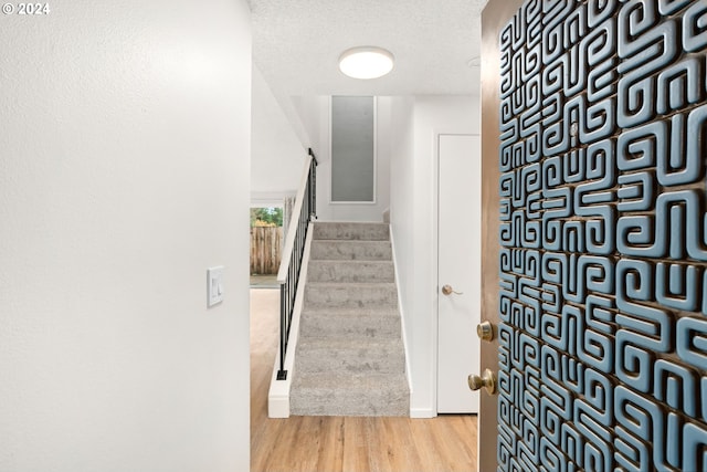 stairs with wood-type flooring and a textured ceiling