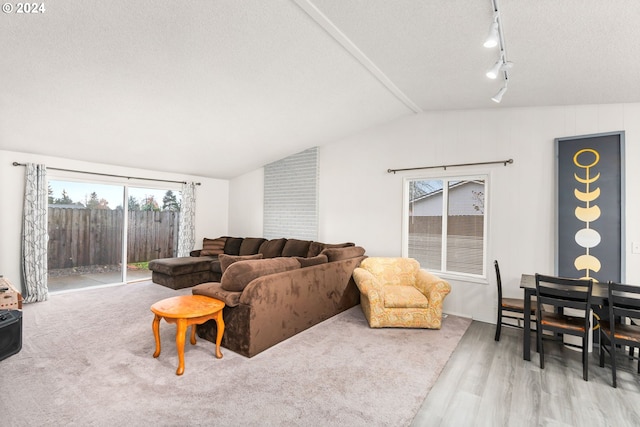 living room featuring a textured ceiling, track lighting, light hardwood / wood-style floors, and vaulted ceiling