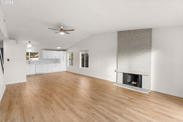 unfurnished living room featuring ceiling fan, light hardwood / wood-style flooring, and a brick fireplace