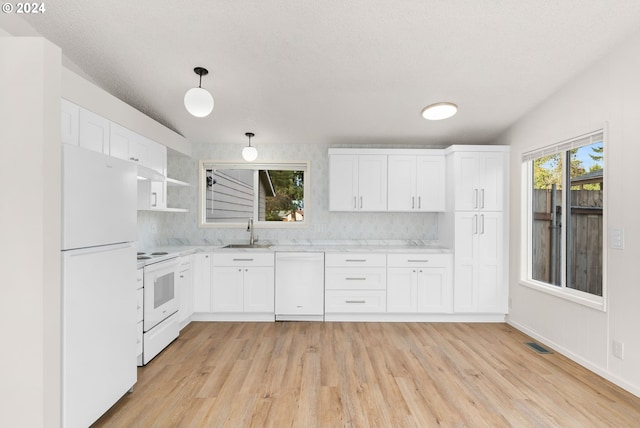 kitchen featuring white appliances, white cabinets, sink, hanging light fixtures, and light hardwood / wood-style flooring