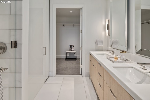 bathroom with double vanity, tile patterned flooring, a sink, and a walk in closet