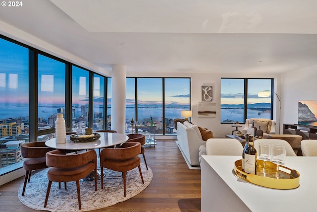 dining room with dark wood-style flooring, a water view, and floor to ceiling windows