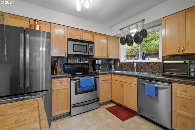 kitchen with backsplash, sink, stainless steel appliances, and light tile flooring