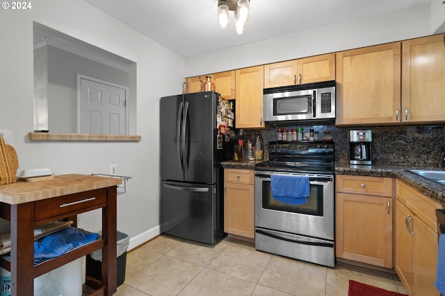 kitchen with backsplash, appliances with stainless steel finishes, dark stone counters, and light tile floors