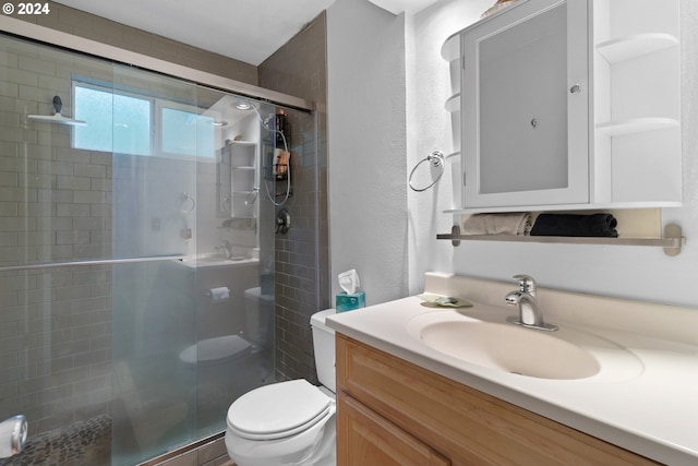 bathroom featuring vanity, toilet, and a shower with shower door