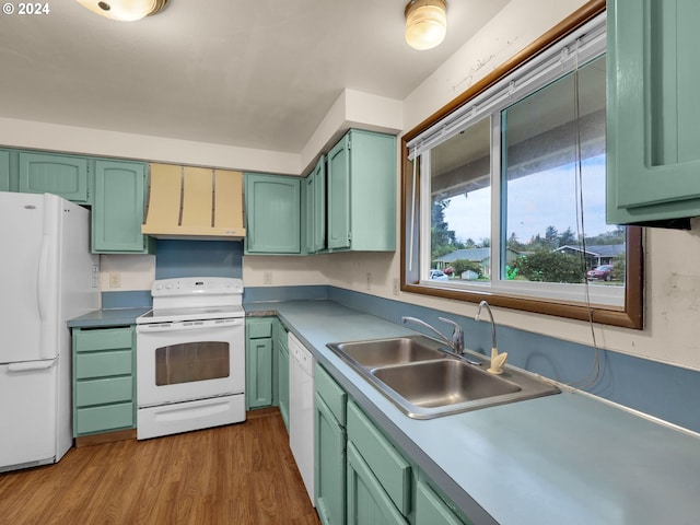 kitchen with range hood, green cabinetry, white appliances, and hardwood / wood-style flooring