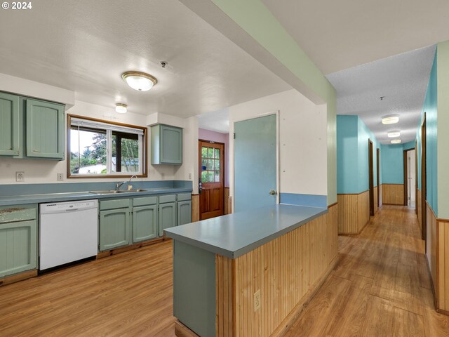 kitchen with white dishwasher, light wood-type flooring, kitchen peninsula, and a wealth of natural light