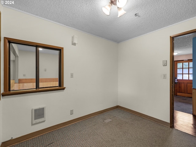 carpeted spare room with a textured ceiling and heating unit