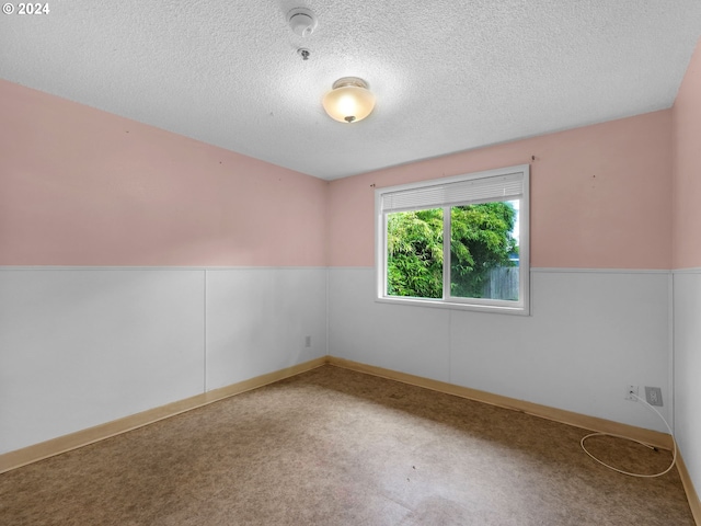 carpeted spare room featuring a textured ceiling