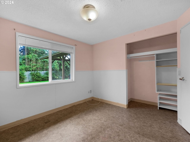 unfurnished bedroom featuring a textured ceiling, a closet, and carpet flooring