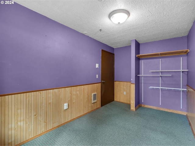 carpeted spare room with a textured ceiling and wood walls