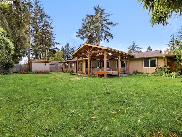 back of house with a storage shed and a yard