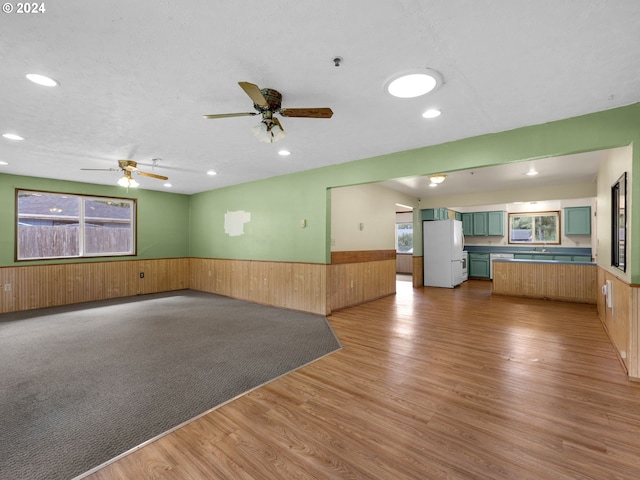 empty room featuring wood-type flooring, a textured ceiling, wooden walls, and ceiling fan