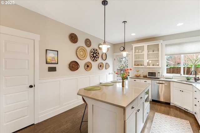 kitchen with white microwave, dark wood finished floors, a sink, glass insert cabinets, and dishwasher