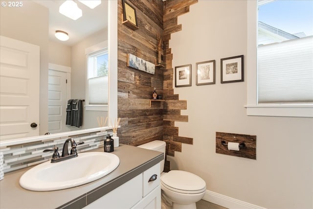 bathroom featuring baseboards, tasteful backsplash, toilet, and vanity