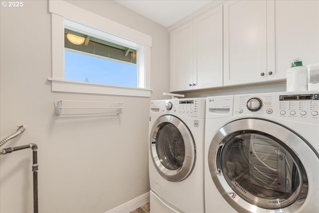 washroom featuring baseboards, cabinet space, and washer and clothes dryer