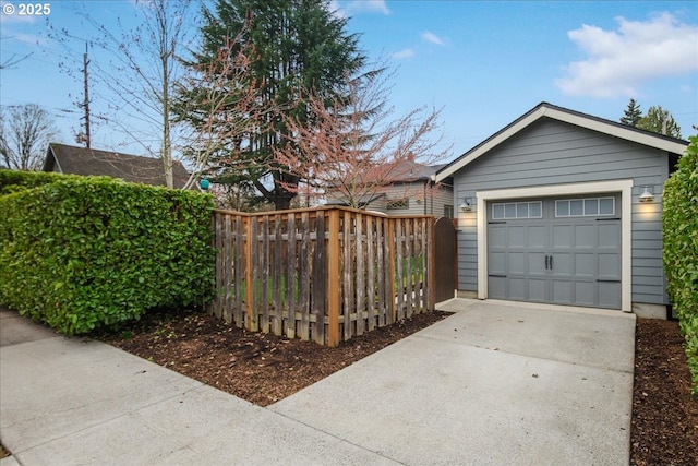 garage featuring driveway and fence