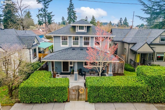 traditional style home featuring a gate, a fenced front yard, and a shingled roof