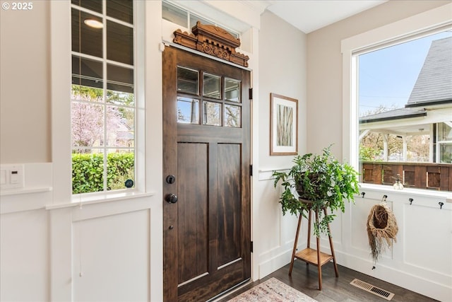 foyer featuring visible vents, plenty of natural light, and dark wood-type flooring