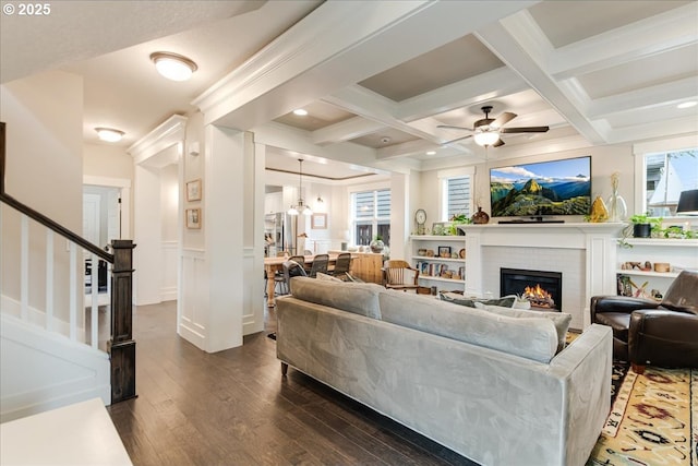 living room featuring beamed ceiling, coffered ceiling, stairs, and dark wood-type flooring