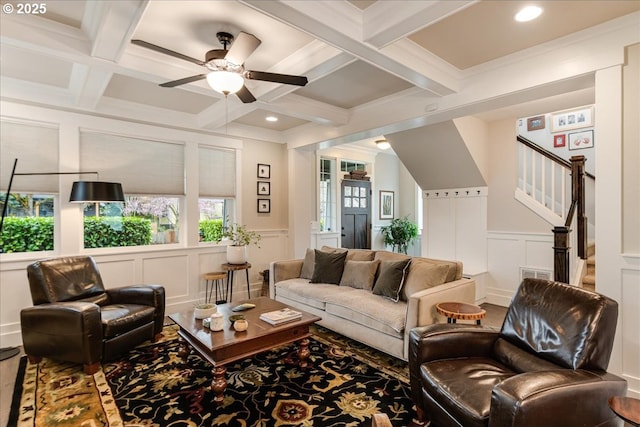 living area with coffered ceiling, beamed ceiling, a decorative wall, and stairway