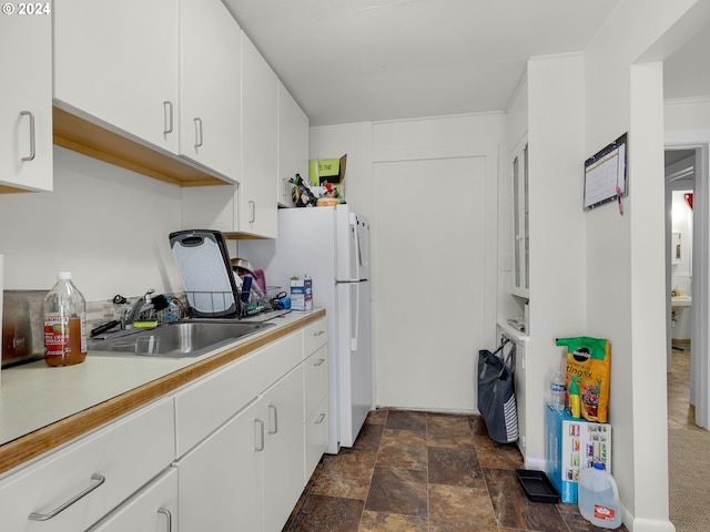 kitchen featuring sink, white cabinetry, and white fridge