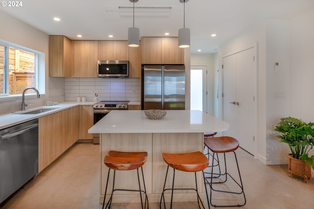 kitchen featuring backsplash, stainless steel appliances, sink, pendant lighting, and a center island