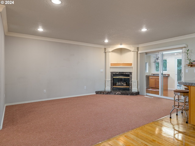 living room featuring a fireplace, wood-type flooring, a textured ceiling, and ornamental molding