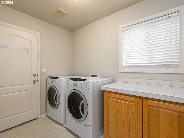 washroom featuring cabinets, independent washer and dryer, and a textured ceiling