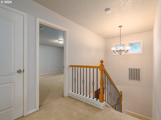 stairs featuring a chandelier, a textured ceiling, and carpet floors