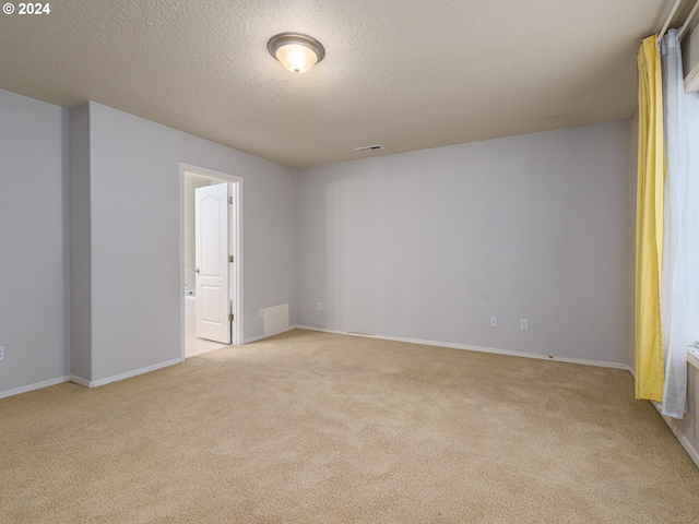 carpeted empty room featuring a textured ceiling