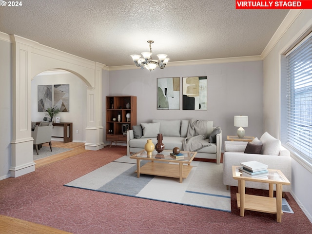 living room featuring ornate columns, plenty of natural light, a chandelier, and a textured ceiling