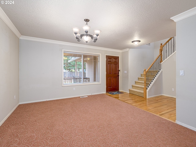 entryway featuring hardwood / wood-style floors, a textured ceiling, ornamental molding, and a notable chandelier