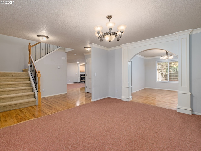 spare room with a textured ceiling, hardwood / wood-style flooring, an inviting chandelier, and crown molding