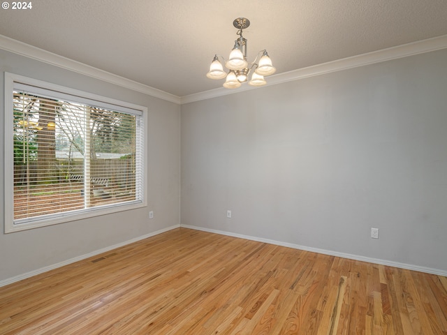 spare room with a textured ceiling, light hardwood / wood-style flooring, a notable chandelier, and crown molding