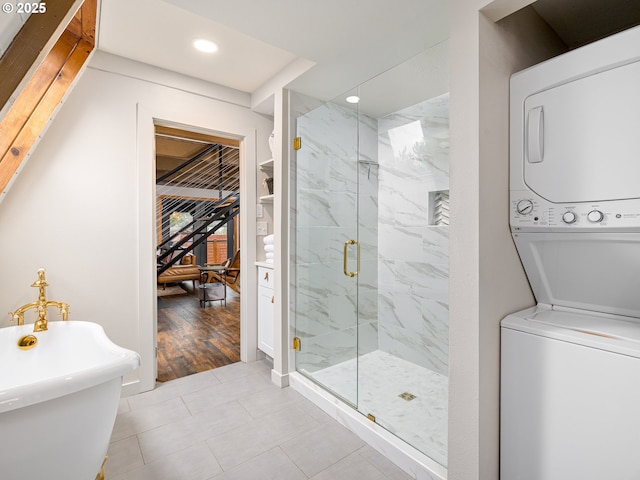 bathroom with shower with separate bathtub, stacked washing maching and dryer, and tile patterned floors