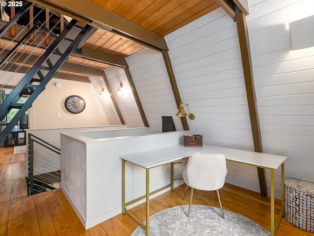 home office with lofted ceiling with beams, wood ceiling, wood walls, and light hardwood / wood-style floors