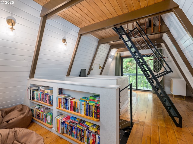 interior space featuring lofted ceiling with beams, wood walls, wooden ceiling, and hardwood / wood-style flooring