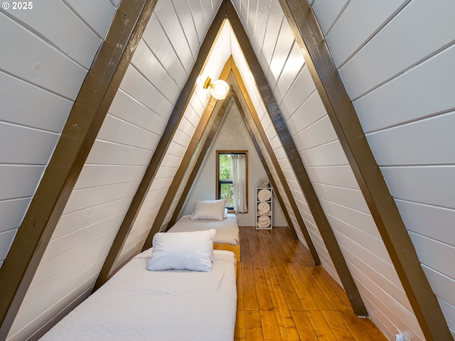 bedroom with hardwood / wood-style floors, vaulted ceiling, and wood walls