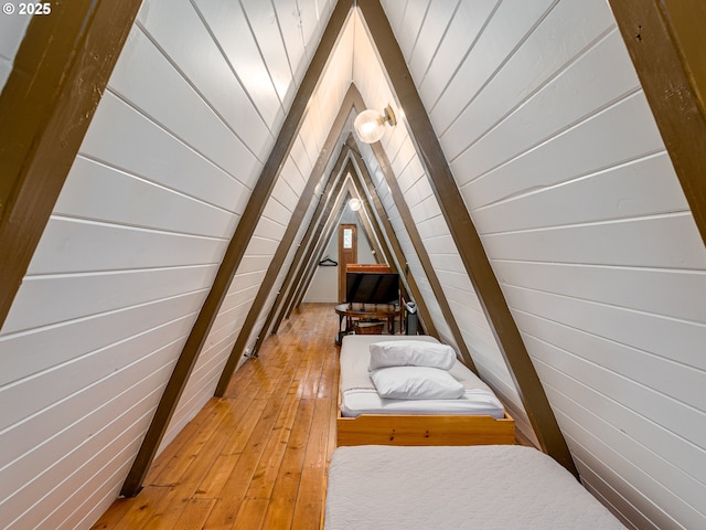 interior space featuring hardwood / wood-style floors, wood walls, and vaulted ceiling