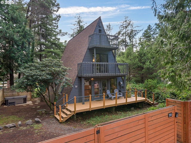 rear view of house featuring french doors, a hot tub, a balcony, and a deck