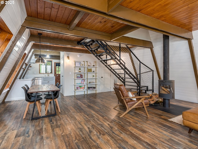 living area featuring dark hardwood / wood-style floors, beam ceiling, a wood stove, and wooden ceiling